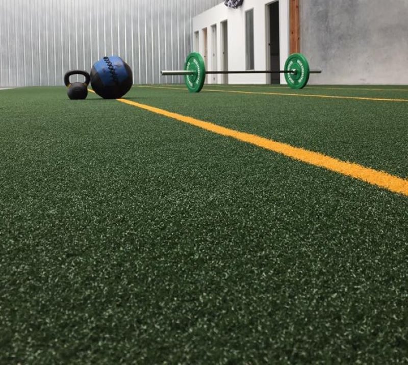 Piso de pasto sintético Gym Grass con demarcación amarilla en zona de ejercicio